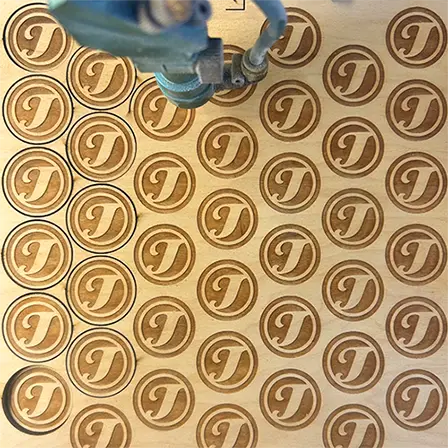 tokens being cut in laser looking straight down from above